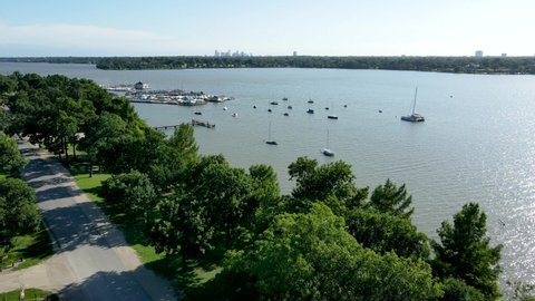 Aerial drone footage over sailboats and docks at White Rock Lake near downtown Dallas Texas during the day in summer