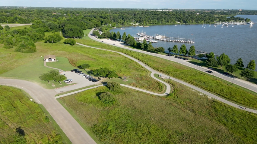 Aerial drone footage over Boy Scout Hill with sailboats and docks in background at White Rock Lake near downtown Dallas Texas during the day in summer
