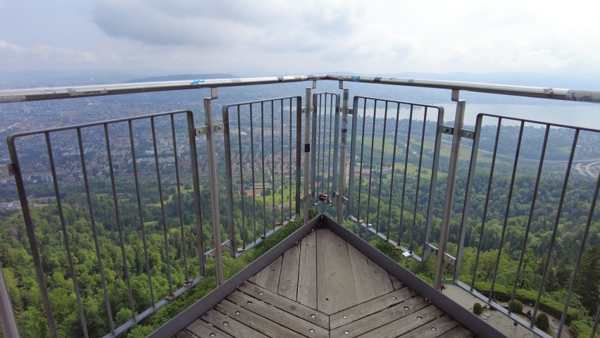 Woman by Zurich panorama on a Swiss lookout tower on Uetliberg mountain in the Swiss plateau, in Switzerland. Canton of Zurich. Carefree girl with open arms looking panorama of Zurich with lake.