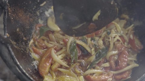 Stirfry vegetables stirred with spatula as camera explores heavy wok