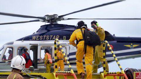 KELANTAN, MALAYSIA - OCT 22nd 2021: Slow motion with soft blur motion footage of unidentified offshore worker carrying luggage and walk to the Weststar Agusta AW139 helicopter to go home.