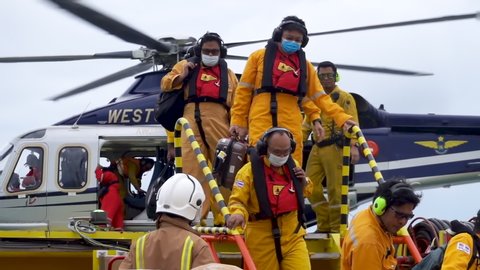 KELANTAN, MALAYSIA - OCT 22nd 2021: Slow motion footage of unidentified offshore workers just arrived at oil and gas platform via Weststar Agusta AW139 helicopter carrying their luggages for duty.
