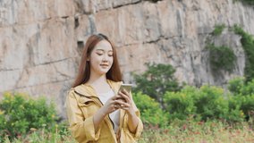 Thai woman taking a selfie and vedio call by smartphone at flower field. Lifestyle of person share to social media (twitter) and using mobile phone via 5g internet to post photo. Technology Concept.