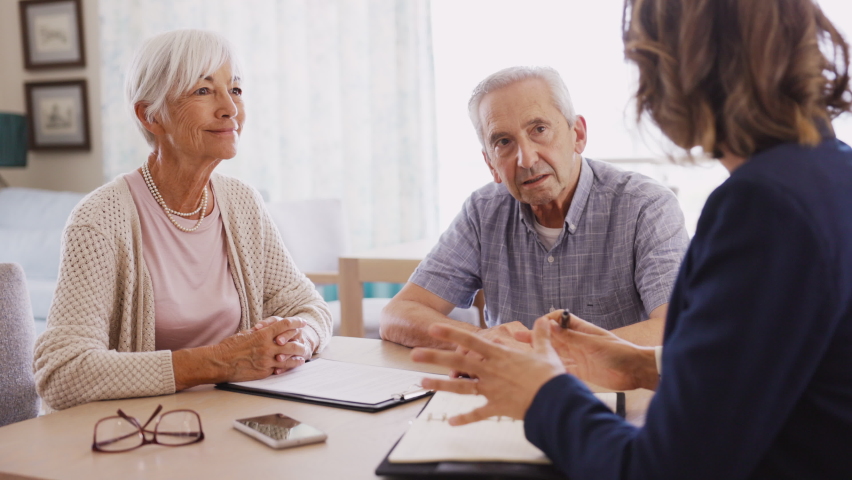 Happy old woman shaking hands with medical adviser for health insurance while sitting at home. Senior couple signing deal for insurance with financial advisor after retirement at home.  Royalty-Free Stock Footage #1075814228