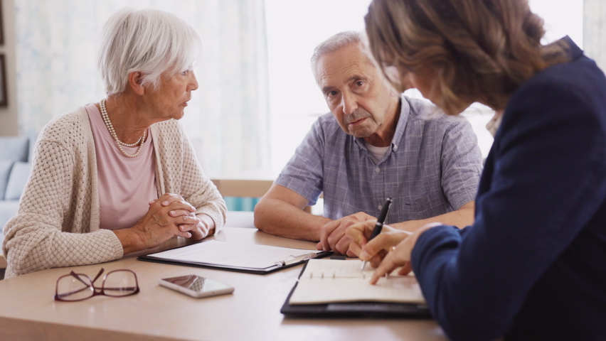 Senior man and woman meeting medical adviser for health insurance. Old couple planning their investments with financial advisor after retirement at home. Aged couple consulting with insurance advisor. | Shutterstock HD Video #1075814231