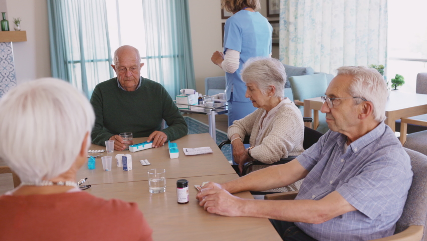 Young nurse in uniform giving medicine to group of seniors at retirement community. Happy smiling nurse gives medicine to elderly patients during her shift in a nursing home. Royalty-Free Stock Footage #1075814273