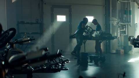 WIDE Kid boy professional racer performing maintenance of his go kart together with trainer. Shot with 2x anamorphic lens
