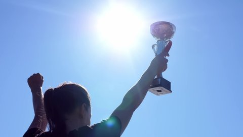 Sportsman with winner gold cup on blue sky background