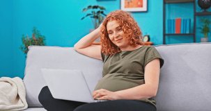 Pregnant woman relaxes on living room sofa with laptop in lap, is on maternity leave, video chats online, talks on camera with doctor, online consultation, pregnancy well-being