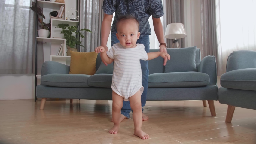 Asian Father Encouraging Smiling Baby Son To Take First Steps And Walk At Home
 | Shutterstock HD Video #1075829552