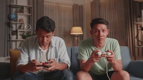 Asian Friends Playing Video Games At Home. Male Happy To Win Victory And Another Man Feeling Disappointed
