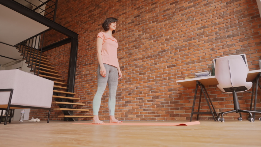 caucasian woman in sportswear standing on yoga mat downward dog stretching at home