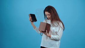 The beautiful and pretty young woman looks into the contents of the gift box, says wow, pleasantly surprised, and embraces the gift with both hands. Asian with dark hair, dressed in a blue blouse