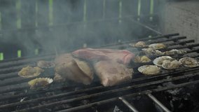 Grilling raw pork meat and scallops in an outdoor charcoal grilling area