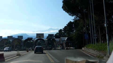 GIARDINI NAXOS, SICILY, ITALY - CIRCA APRIL, 2019: Car windshield view driving through toll booth, famous Sicilian Etna volcano seen in front.