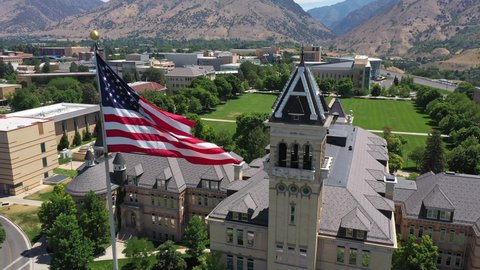 Circa - July, 8, 2021 - Logan Utah - Aerial view of the flag waving looking down at the historic Old Main Building at Utah State University in Logan.