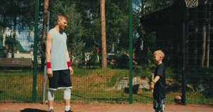 Basketball player give high five to son on basketball court. Dad, child being team. Happy family pastime, support