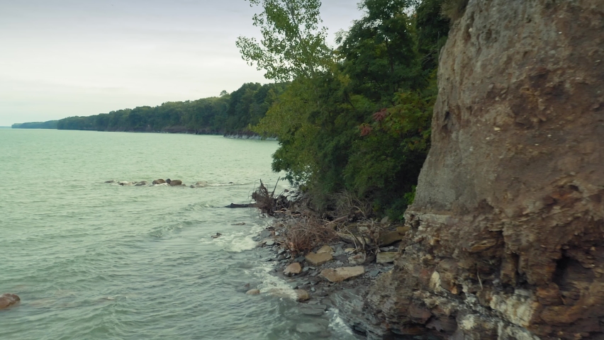 Aerial: Shoreline of the The Great Lake Erie  green forest. Barcelona, New York, USA
