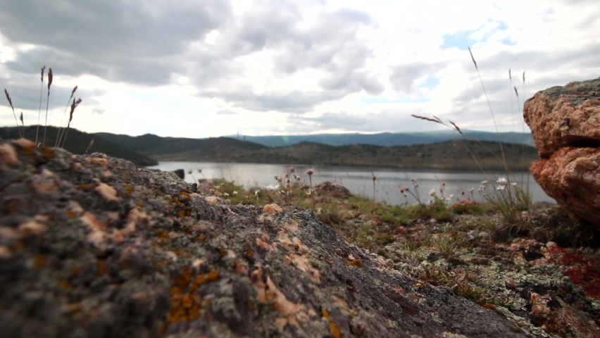 Baikal lake wild rocky bay in a summer tourism cove landscape in a moody day with sky and clouds background and barrens herb mountain foreground.