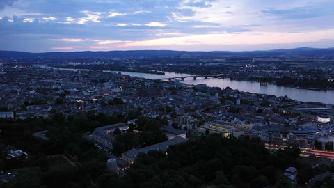 Low Push in Drone shot of Mainz at magic hour night of the city center with with the cathedral and the dark Rhine river water in the background showing a colorful sky