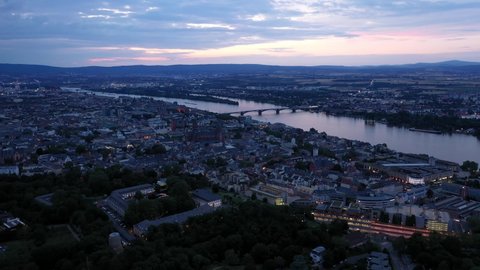 Approaching aerial Drone shot of Mainz at magic hour night towards city center with with the cathedral and the dark Rhine river water in the background showing a colorful sky