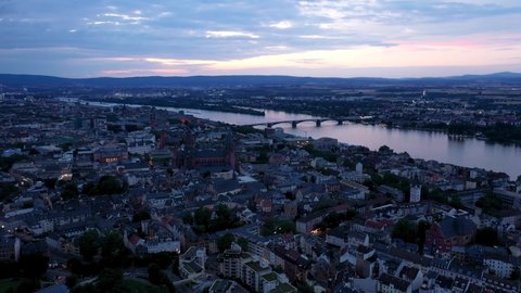 Revealing Drone shot of Mainz at magic hour night showing a colorful sky and reflections of the Rhine river water in the background