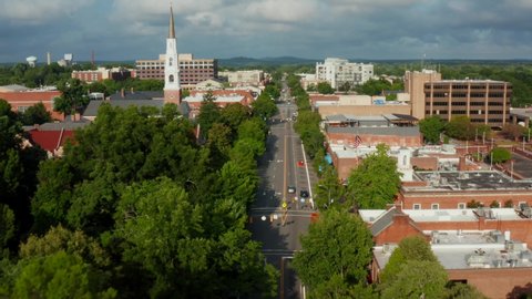 Chapel Hill, North Carolina, home of UNC. Aerial flight through town above East Franklin Street. American flag waves in breeze.
