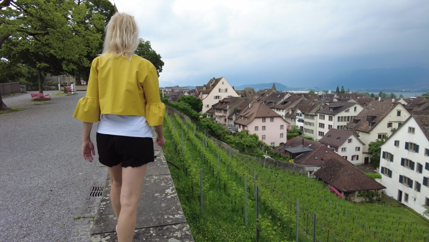 Woman with short skirt walking on top of Rapperswil-Jona village city by Zurich Lake in Switzerland. Aerial view of terraced vineyards of Rapperswil-Jona cityscape in Swiss canton of St. Gallen.