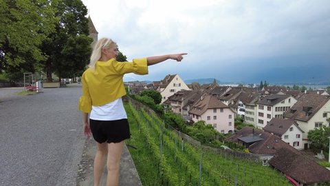 Woman with short skirt walking on top of Rapperswil-Jona village city by Zurich Lake in Switzerland. Aerial view of terraced vineyards of Rapperswil-Jona cityscape in Swiss canton of St. Gallen.