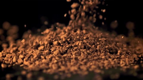 Super slow motion soluble coffee pellets fall on the table. On a black background.Filmed on a high-speed camera at 1000 fps.