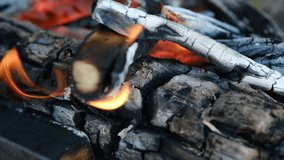 Close up of beautiful and soothing video of calming fire smoldering and coals with flying small sparks. Burning logs. Summer vacation concept. Natural background. Slow motion