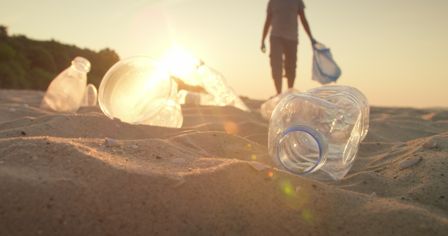 An active volunteer collects plastic garbage and puts it in a bag on the city beach, the society against Pollution. Sorting plastic bottles for recycling. Concept of ecology. Royalty-Free Stock Footage #1075869485
