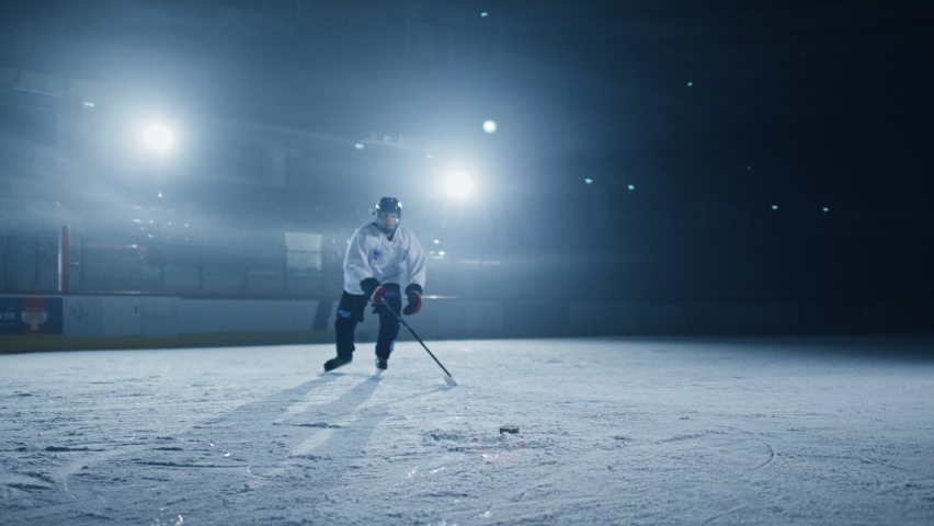 Ice Hockey Rink Arena: Professional Player Shooting, Hitting, Stricking the Puck with Hockey Sticks. Athlete Scoring a Goal. Dramatic Wide Shot, Cinematic Lighting, 3D Puck Flying in Slow Motion Royalty-Free Stock Footage #1075879991