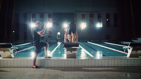 Swimming Pool: Professional Trainer Training Future Champion Swimmer. Swimmer Dives and Trainer Times Lap with Stopwatch. Team Ready for World Record and Victory. Cinematic Wide Slow Motion
