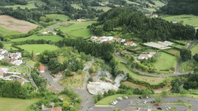 Drone shot of hot springs in Furnas village, Sao Miguel Island, Azores, Portugal, Europe. Panoramic view of green landscape with steaming geothermal pools of Caldeiras das Furnas, 4k footage