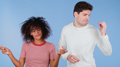 Young african american woman and white man dancing isolated on blue background. Party, happiness, music, Interracial couple concept. 