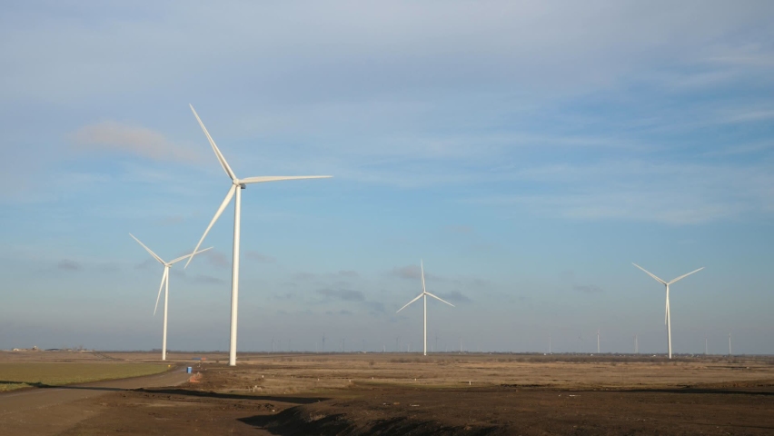 Four electrical wind mills with long propellers rotating slowly in steppe in summer 