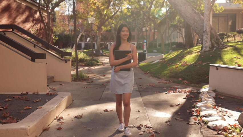 Cute Asian female college student walking toward the camera.
