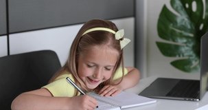 Caucasian little girl school pupil studying online from home, watching web class lesson or listening tutor by video call elearning during coronavirus covid-19 pandemic self isolation. Slow motion