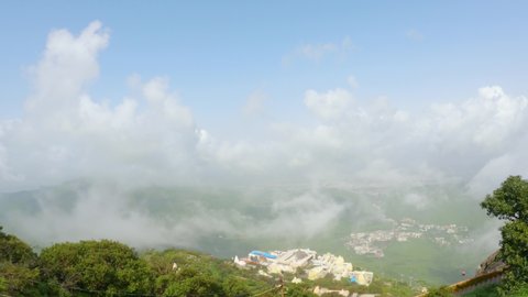 4k Footage. Timelapse of the clouds cover Neminath Jain temple and Junagadh city, View from Girnar hills. Foggy  mountain valley during Monsoon season. Ecology and environment conservation
