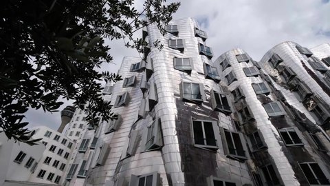 DÜSSELDORF, GERMANY - JULY 05, 2021: Famous shiny metal bulding of Neuer Zollhof in Media Harbor (Medienhafen), designed by Frank O. Gehry, completed in 1998. Spectacular postmodern architecture, 4k.
