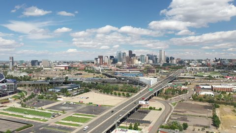 Aerial View of Highway Traffic and Downtown Denver Colorado, USA in Background. MIle HIgh Neighborhood and Central Buildings on Sunny Day, Drone Shot