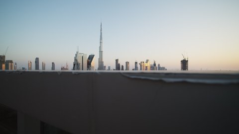 Reveal of urban city center of Dubai with Burj Khalifa during sunset. Busy city traffic and tall skyscrapers in Dubai, United Arab Emirates in 2021