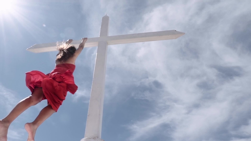 Hispanic woman hanging from a cross on the top of a mountain. Slow-motion.