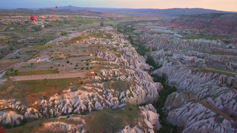 Goreme, Cappadocia, Turkey - May 27, 2021: Ballooning in Kapadokya. Many hot air balloons flying over spectacular breathtaking unusual valleys and rocks in blue sunrise morning sky.  