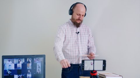 Learning English remotely online. A bald man with a beard gives a grammar lesson using flashcards to learn letters. Man in headphones and microphone