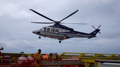 KELANTAN, MALAYSIA - OCT 22nd 2020 : Slow motion footage of Weststar AW139 helicopter on air loaded with onshore passengers ready for landing on helicopter deck at oil and gas platform.