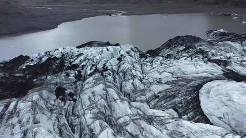Jagged ice flowing down mountain as Glacier, Sólheimajökull, aerial