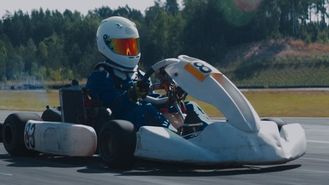 TRACKING Front view of teenager professional racer driving his go kart on a race track. Shot with 2x anamorphic lens