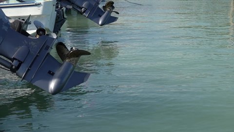 Outboard engines with propellers on parked boats. 